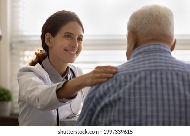 Smiling Young Caucasian Female Doctor Comfort Support Old Male Patient At Consultation In Hospital. Happy Woman GP Touch Caress Man Client In Clinic, Show Good Medical Service. Healthcare Concept.