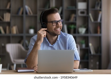 Smiling Young Caucasian Male Employee In Headphones Work Distant On Laptop At Home Office Thinking Dreaming. Happy Millennial Man In Earphones Busy Using Computer Talk On Video Call With Client.