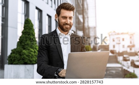 Smiling Young Caucasian Man Using Laptop Outdoors At Modern Office, Business Concept