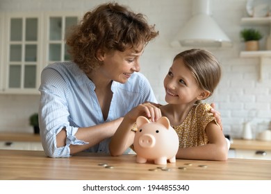 Smiling young Caucasian mom and little daughter put coins money into piggybank mange family budget together. Happy mother and small girl child saving for future feel economical provident. - Powered by Shutterstock