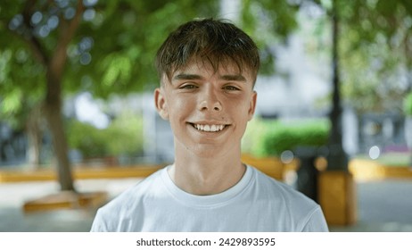 Smiling young caucasian teen boy portrait in city park with blurry green background - Powered by Shutterstock