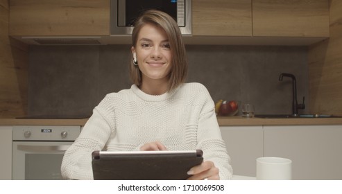 Smiling young caucasian woman blogger vlogger influencer sit at home kitchen speaking looking at camera talking make video chat, conference call record lifestyle blog vlog, webcam view