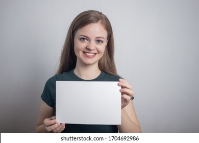 Smiling Young Caucasian Woman Girl Holding Blank White Paper Sheet With Copy Space