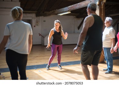 Smiling young caucasian woman showing dance moves. Female dance teacher giving dance class to seniors in studio. Dance, hobby, healthy lifestyle concept - Powered by Shutterstock