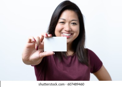 Smiling Young Chinese Woman Holding Up A Blank White Business Card On Display In A Concept Of Identification, Qualifications, Contact Or Branding, Focus On Card