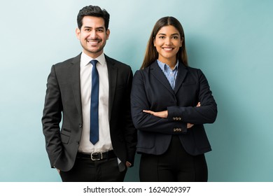 Smiling young colleagues in suit standing against blue background