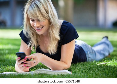 Smiling Young College Girl Texting On A Cell Phone