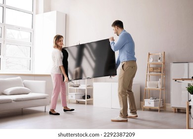 Smiling Young Couple Carrying New Television At Home
