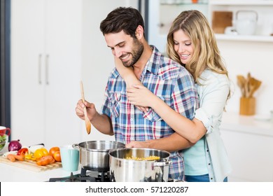 Smiling young couple cooking food in the kitchen - Powered by Shutterstock