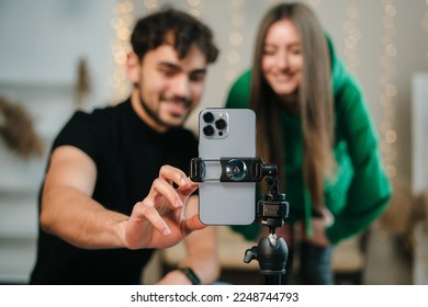 Smiling young couple with happy faces looking at phone camera, bloggers recording videoblog at home. Video live streaming.