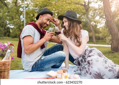 Smiling Young Couple Having Picnic And Drinking Wine Outdoors