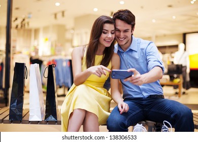 Smiling Young Couple Looking At Mobile Phone