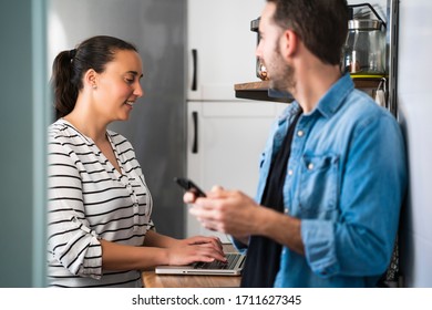Smiling Young couple of man and woman using their laptop in the kitchen of their apartment. Work at home and stay home safely - Shutterstock ID 1711627345