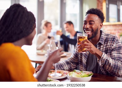 Smiling Young Couple On Date Making Toast Before Enjoying Pizza In Restaurant Together