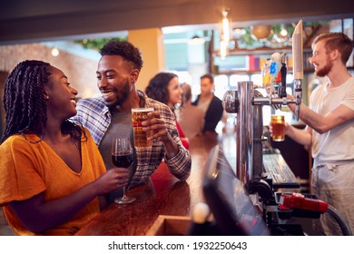 Smiling Young Couple On Date Sitting At Counter Of Busy Bar - Powered by Shutterstock