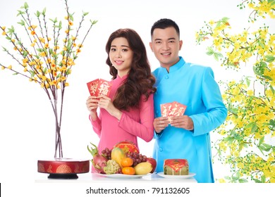 Smiling young couple in traditional dresses holding lucky money envelopes