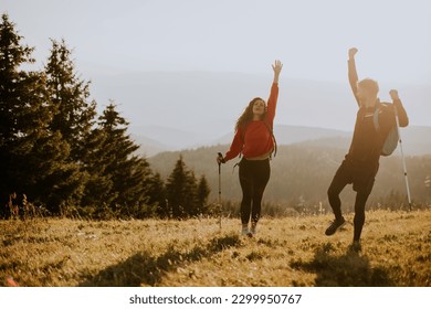 Smiling young couple walking with backpacks over green hills - Powered by Shutterstock