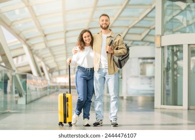 Smiling young couple walking hand in hand in an airport corridor signifies the joy of traveling together
