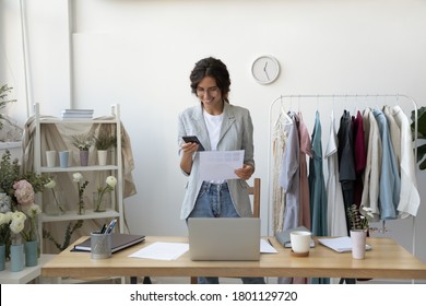 Smiling young creative decorator holding color pattern paper document, placing order online in internet store using mobile application or communicating with client in social network via smartphone. - Powered by Shutterstock