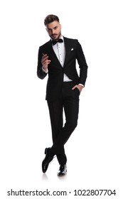 Smiling Young Elegant Man In Tuxedo Is Smoking A Cigarette On White Background