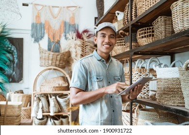 smiling young entrepreneur looks at the camera while holding a digital tablet while standing in a craft shop - Powered by Shutterstock