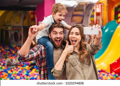 Smiling Young Family With Their Little Son Spending Time Together At The Entertainment Centre