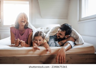 Smiling young family watching TV together. They are spending free time at home and have fun. - Powered by Shutterstock