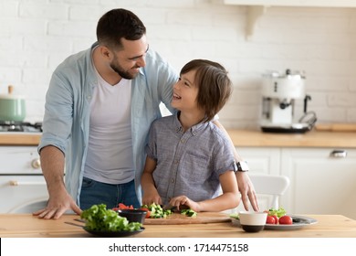 Smiling young father teaching little kid son chopping fresh vegetables for healthy vegetarian dinner, enjoying spending time together in kitchen. Happy child boy learning cooking with dad at home. - Powered by Shutterstock