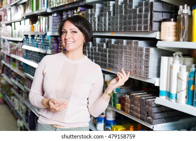 Smiling Young Female Choosing Box Of Hair Dye In Shop