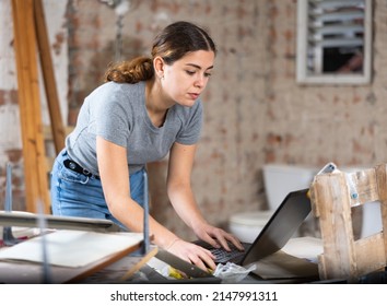 Smiling young female design architect with laptop examining construction site and planning concept of modification of building interior structure