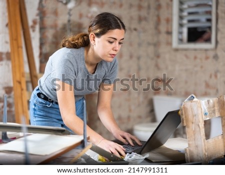 Smiling young female design architect with laptop examining construction site and planning concept of modification of building interior structure
