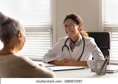 Smiling Young Female Doctor Talk Consult Mature Patient At Consultation In Private Clinic. Happy Caring Woman GP Or Therapist Have Meeting With Senior Client In Hospital. Elderly Healthcare Concept.