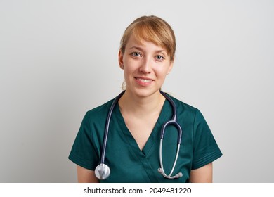 Smiling Young Female Expert Trustworthy Nursing Assistant With Phonendoscope In Green Uniform. Healthcare Worker In Clinic. Portrait Of Professional Paramedic. Horizontal Of Family Resident Physician