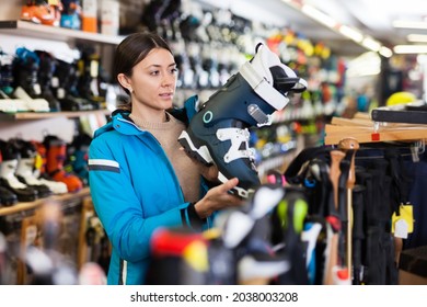 Smiling young female looking for new ski boots in a ski equipment shop