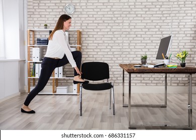 Smiling Young Female Manager Sitting On Chair Stretching Her Arms