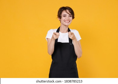 Smiling Young Female Woman 20s Barista Bartender Barman Employee In White T-shirt Apron Working In Coffee Shop Pointing Index Fingers On Camera Isolated On Yellow Color Background Studio Portrait