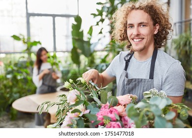 Smiling young florist in training while tying bouquet