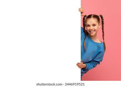 Smiling young girl with braided hair peeking from behind a blank white board against pink background - Powered by Shutterstock