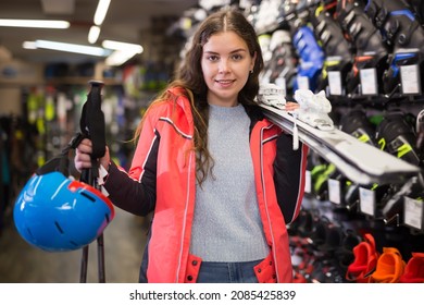 Smiling Young Girl Chose Skis, Shelm And Boots In A Sports Equipment Store