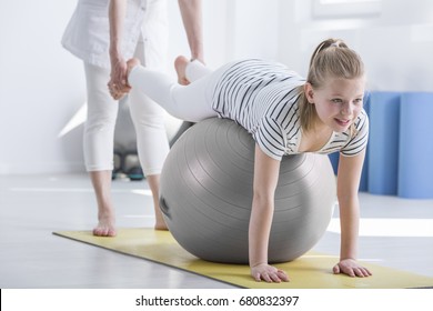 Smiling Young Girl Lying On Ball During Pediatric Occupational Therapy