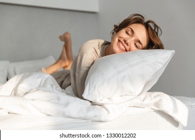 Joven sonriente relajándose en la cama por la mañana
