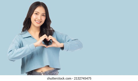 Smiling young girl showing heart with two hands, love sign Isolated over light blue background Portrait young beautiful asian woman hand gesturing in heart shape Smile face asian girl get in love - Powered by Shutterstock