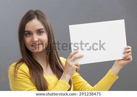 smiling young girl wearing yellow holding a marketing message on a copy space board