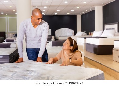 Smiling Young Glad Beautiful Latina Woman With Her Boyfriend Choosing New Modern Orthopedic Mattress In Furniture Shop