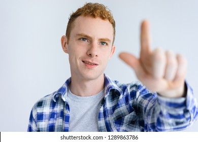 Smiling young guy touching invisible wall. Handsome business man standing and pointing at something. Promotion concept. Isolated front view on white background. - Powered by Shutterstock