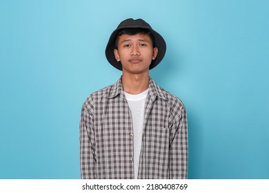 Smiling Young Handsome Asian Boy Using Flannel Shirt And Bucket Hat Standing Over Isolated Blue Background.