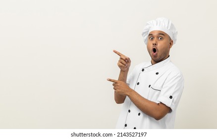 Sonriente Joven y guapo chef asiático con uniforme, con el dedo apuntando hacia un espacio aislado en blanco para el texto. Cocinero El chef de Ocupación o el panadero La gente en el restaurante de cocina y el hotel.