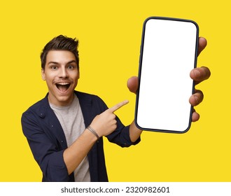Smiling young and handsome man holding mobile phone with white screen, offering ample copy space. Image is isolated on clean white background, creating versatile canvas for various design needs. High - Shutterstock ID 2320982601