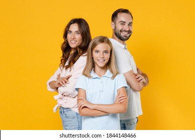 Smiling Young Happy Parents Mom Dad With Child Kid Daughter Teen Girl In Basic T-shirts Holding Hands Crossed Isolated On Yellow Background Studio Portrait. Family Day Parenthood Childhood Concept