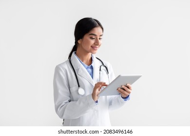 Smiling Young Hindu Woman Doctor In White Coat Work On Tablet, Isolated On White Background. Modern Device For Remote Online Consultation, Social Distance And New Normal With New Medical Application